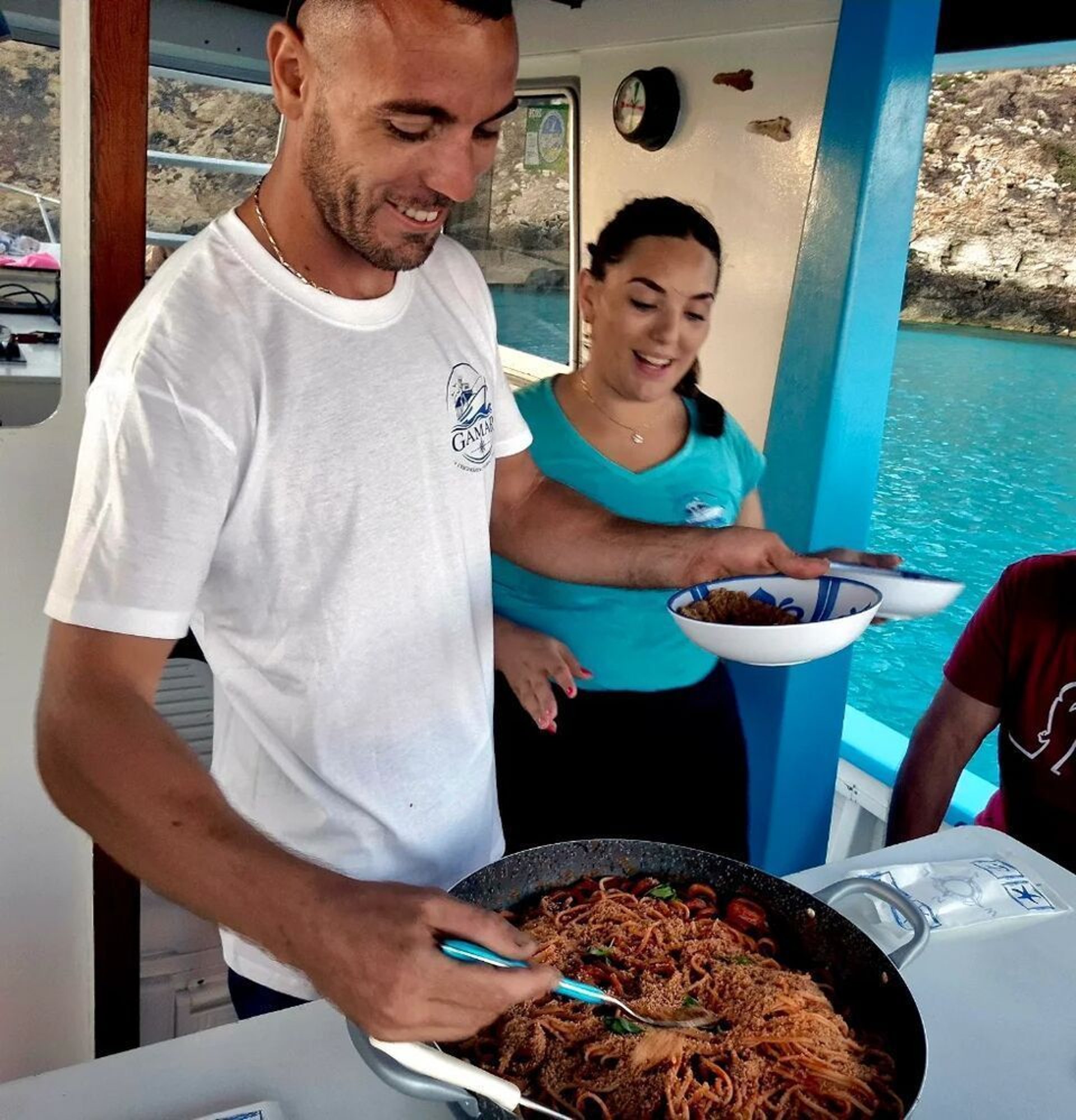 Natale e Miriam servono la pasta agli ospiti a bordo