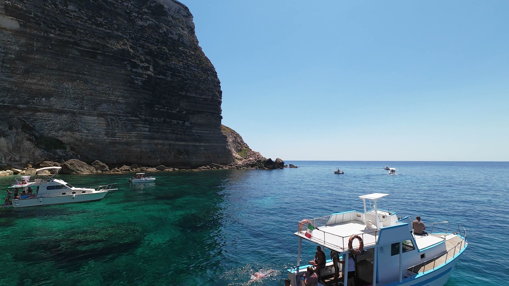 La Barca Gamar vicino alla falesia alta con ospiti in acqua